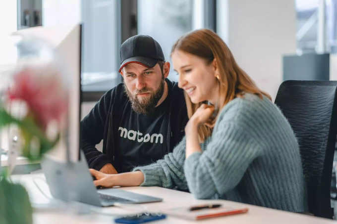 Heldency GmbH - Online Marketing Agentur - Marco Reinhold und Anna Katharina Blume-van Landeghem schauen gemeinsam optimistisch auf ein Notebook